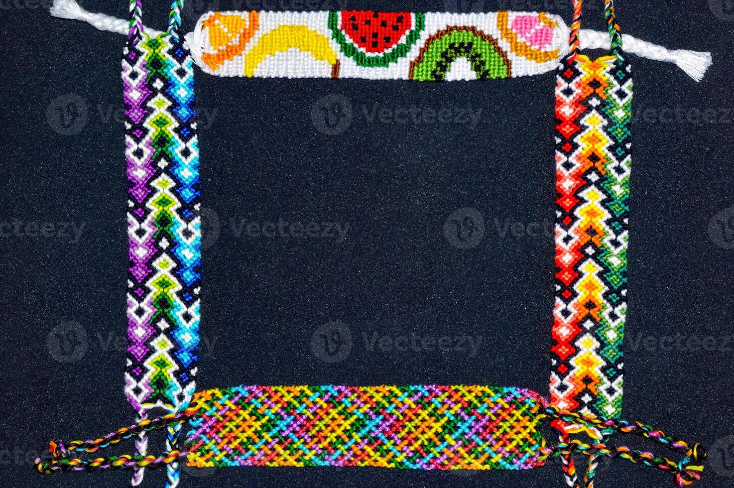 Frame made of braided woven colorful friendship bracelets on black background. Copy space photo