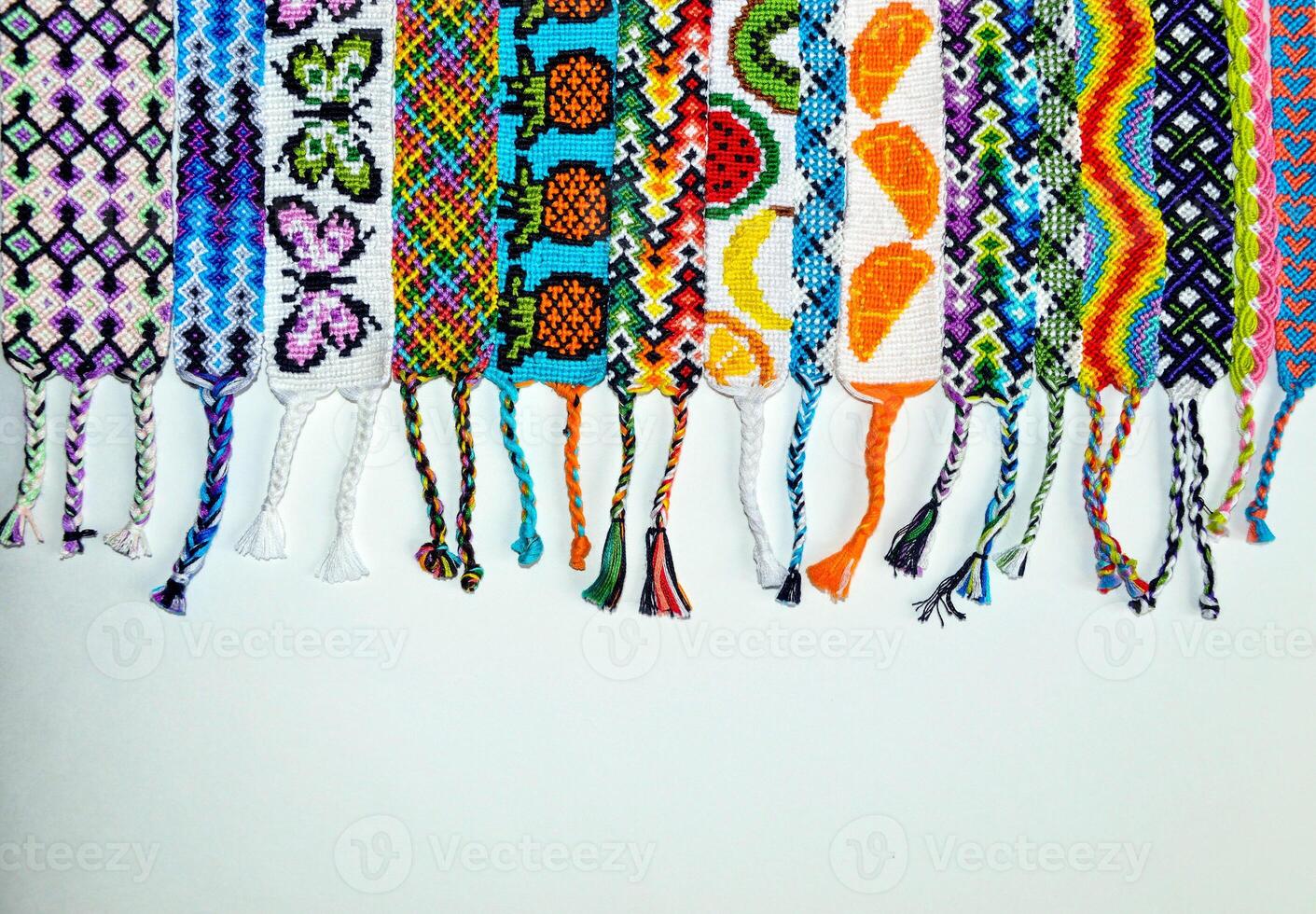 Multi-colored woven DIY friendship bracelets handmade of embroidery bright thread with knots isolated on white background photo