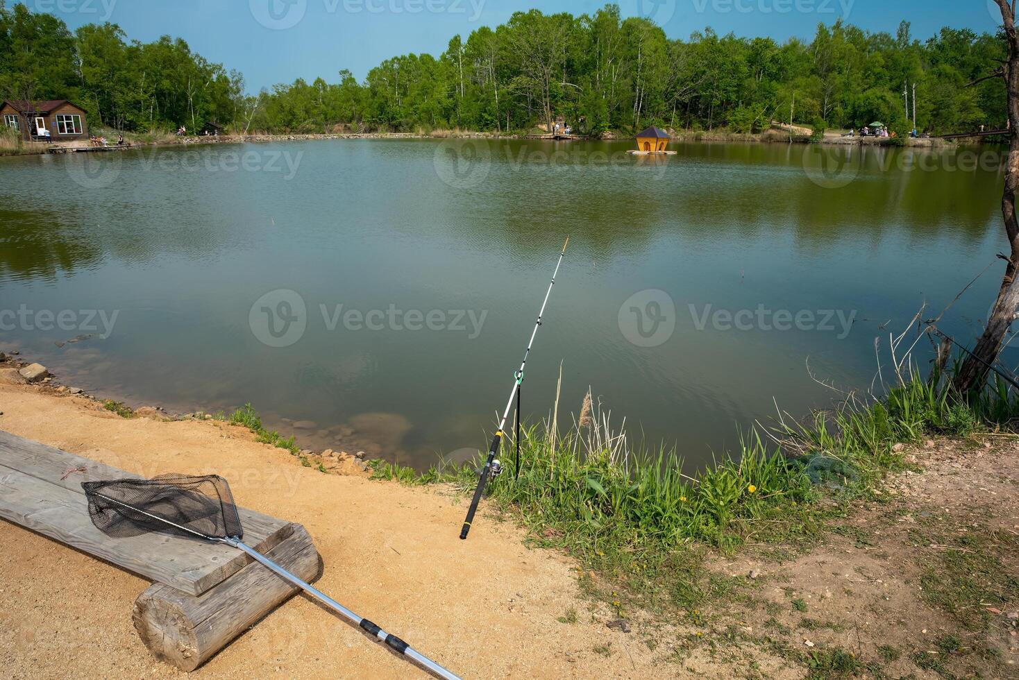 fishing rod and net for fishing against the backdrop of a pond and forest. summer activities photo