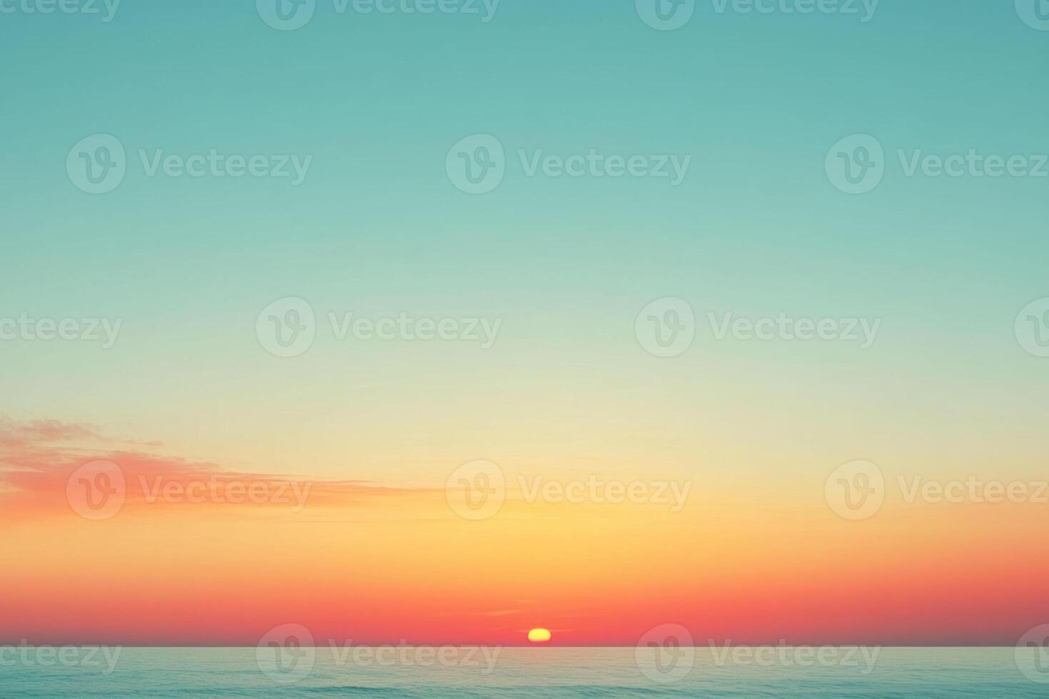 A sunset over the ocean with a blue sky photo