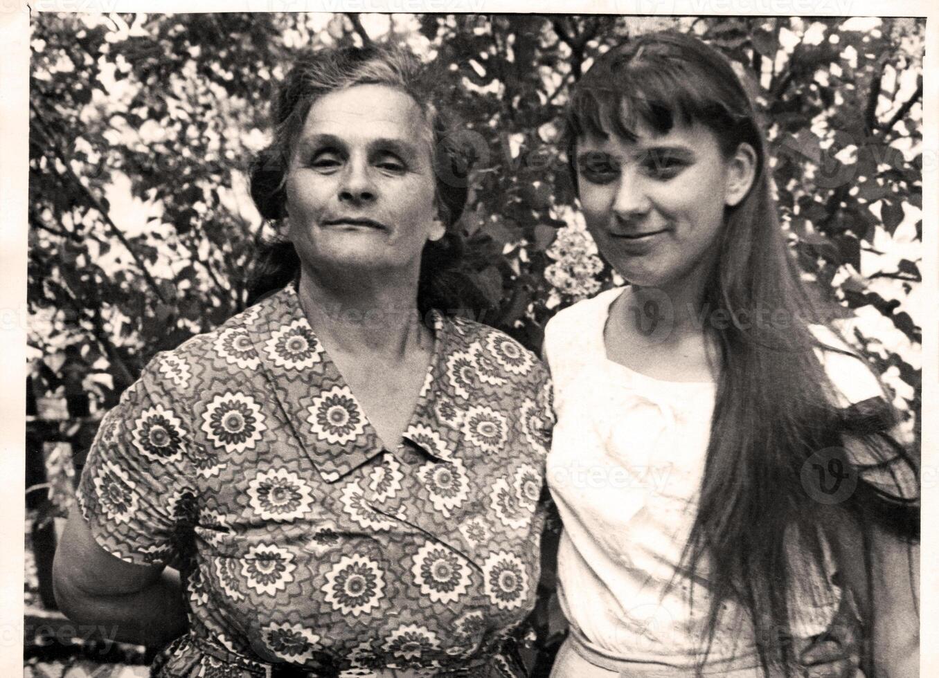 Retro portrait of mother and daughter in summer garden. Vintage photo 1972.