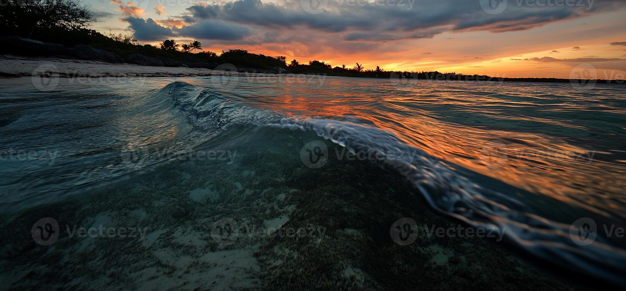A sunset over the ocean with a wave breaking on the shore photo