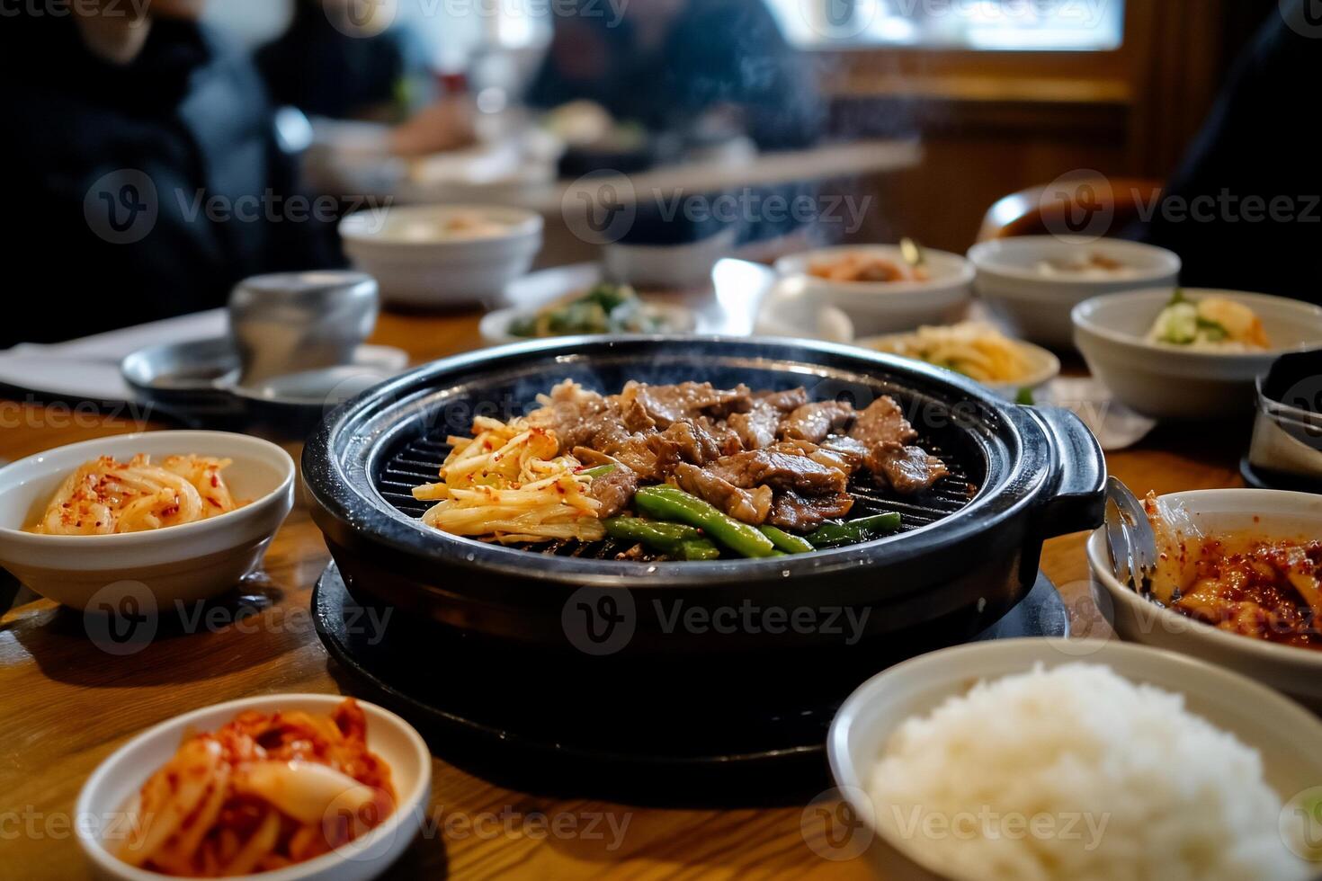 Delicious Korean BBQ feast. A tabletop grill is centered, sizzling with marinated meats, vegetables, and other sides photo