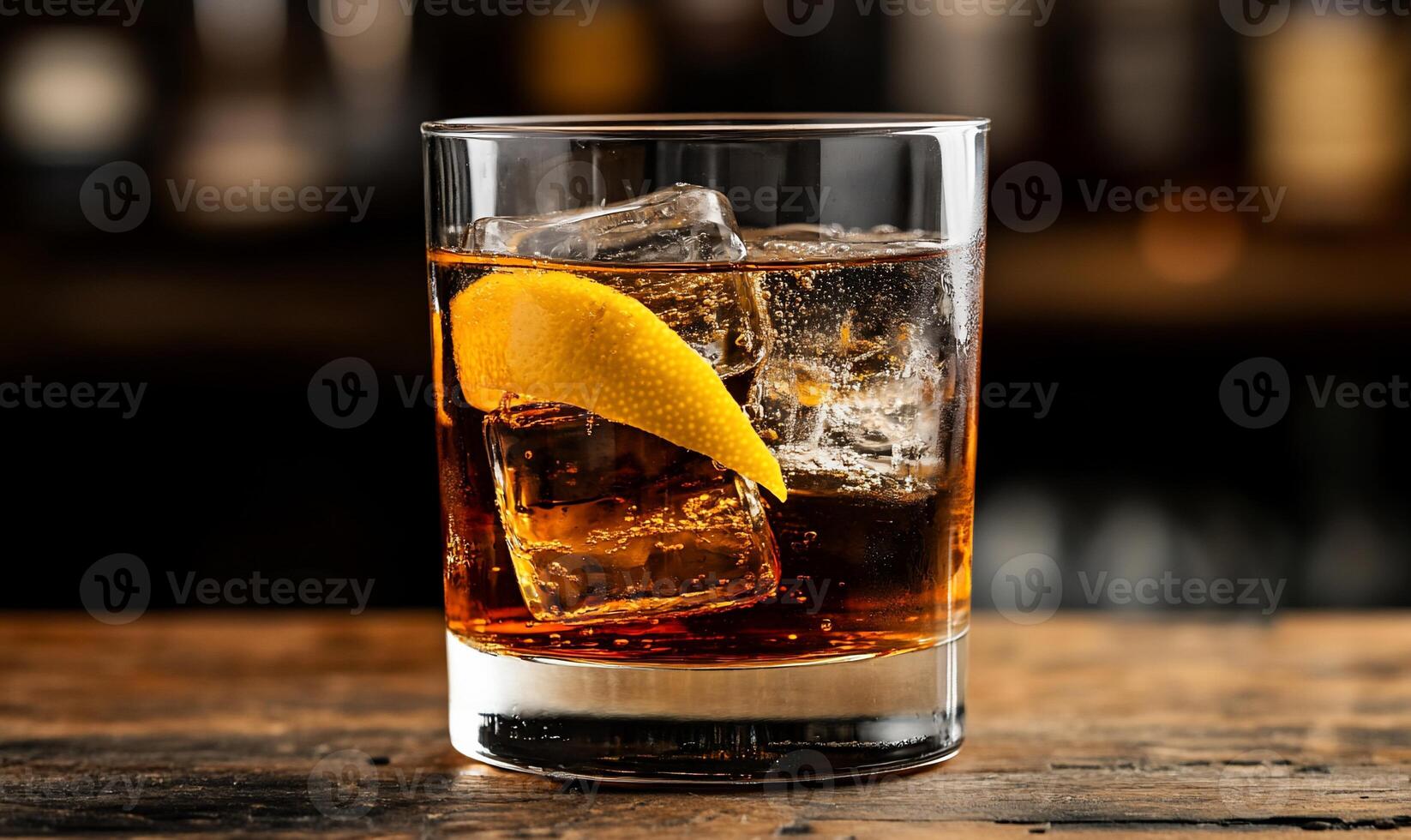 A Classic Whiskey Cocktail. Ice cubes and a lemon peel garnish adorn a dark amber drink in a rocks glass. The drink sits on a wooden bar top photo
