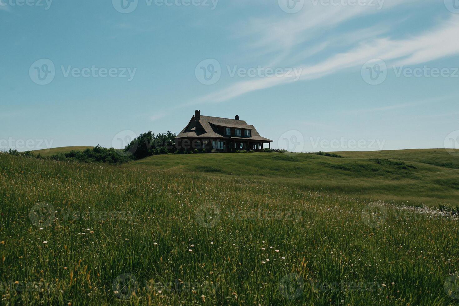 Rustic home nestled on a grassy hill under a clear sky photo