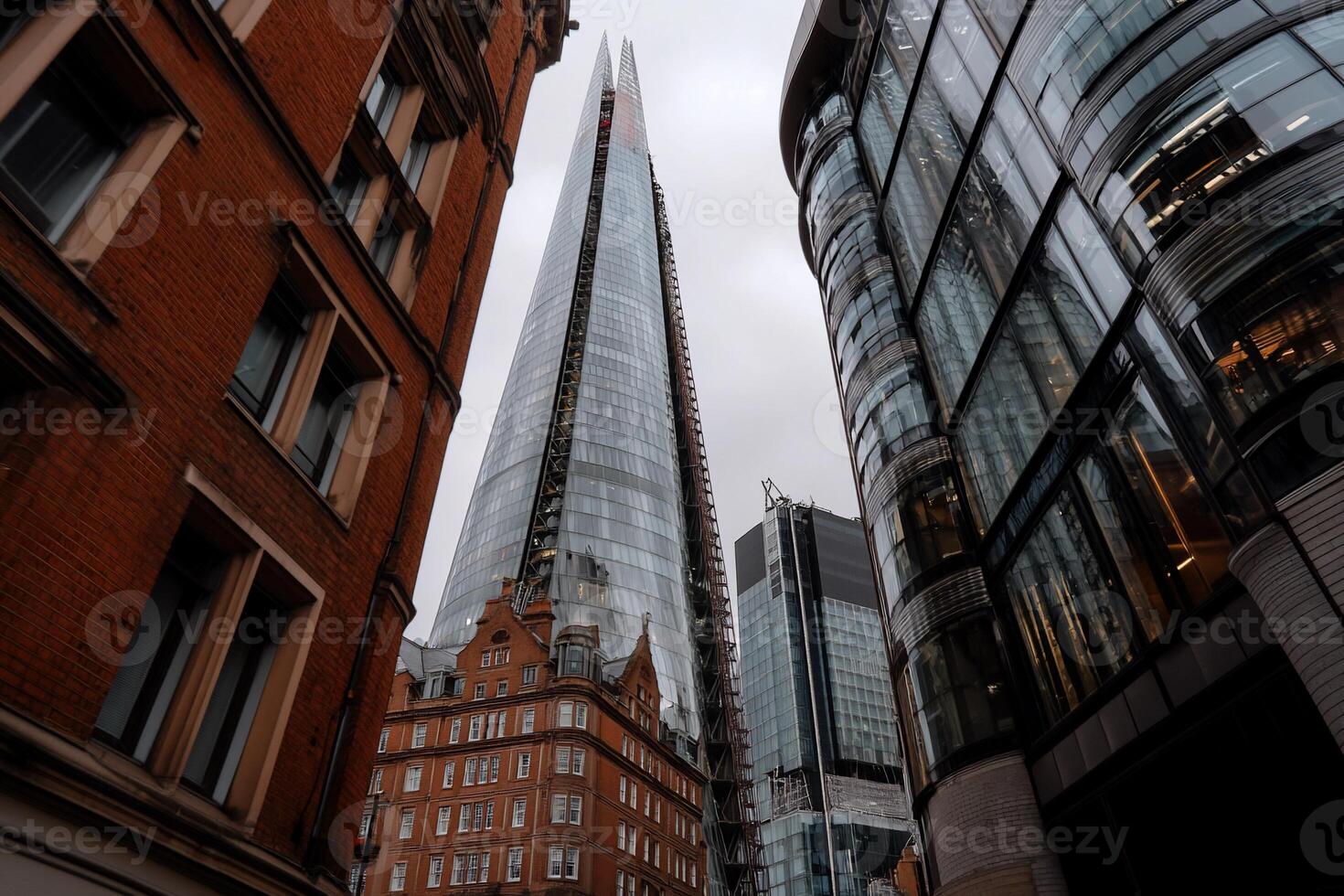 London skyscraper amidst historic buildings. View from street level, looking up at modern high-rise photo