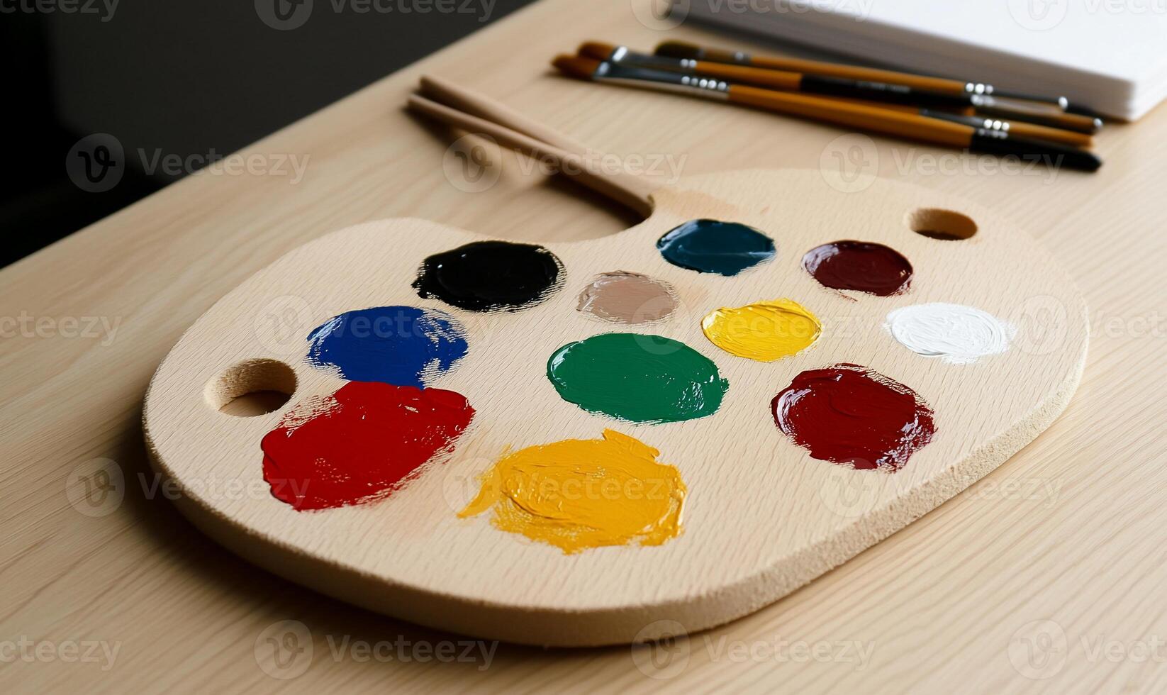 Wooden artist's palette with assorted paint colors and brushes photo
