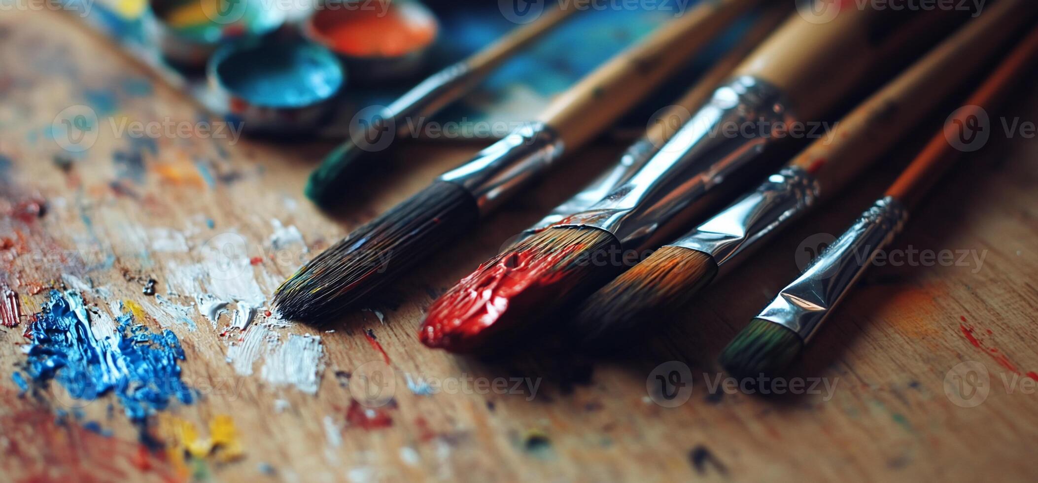 Paintbrushes rest on a palette with vibrant paint photo