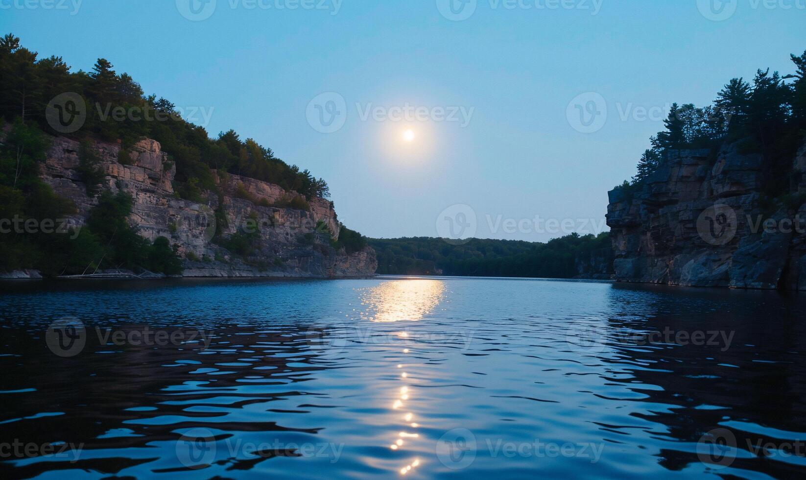 Serene lake at dusk with a full moon reflecting. Rocky cliffs frame the tranquil water photo