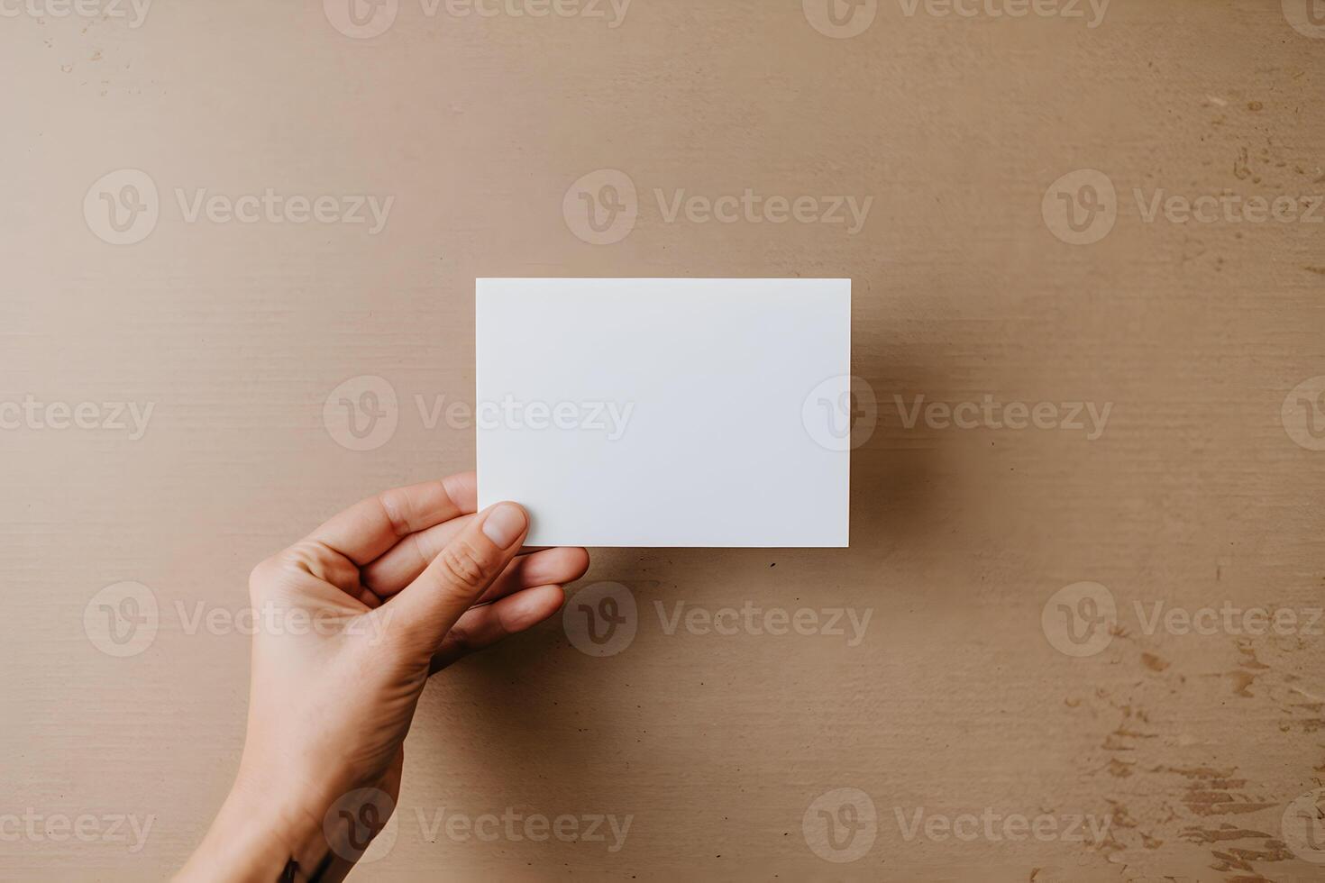 Hand holds a blank white card against a textured cardboard surface, focusing on versatility photo