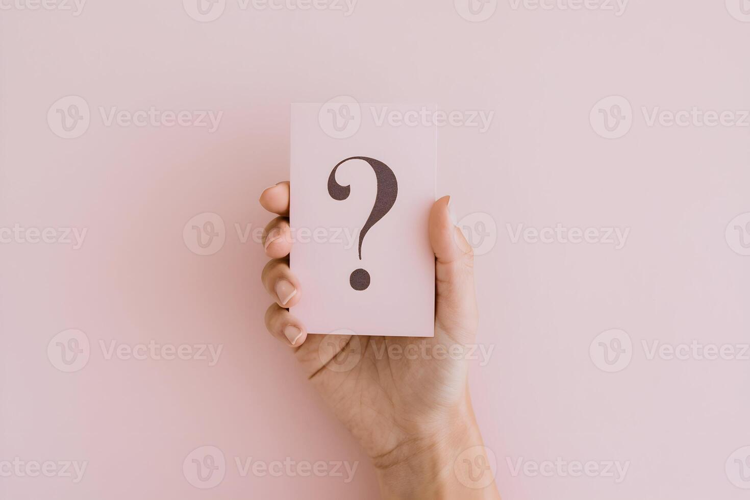 Hand holding a pink card with a black question mark photo