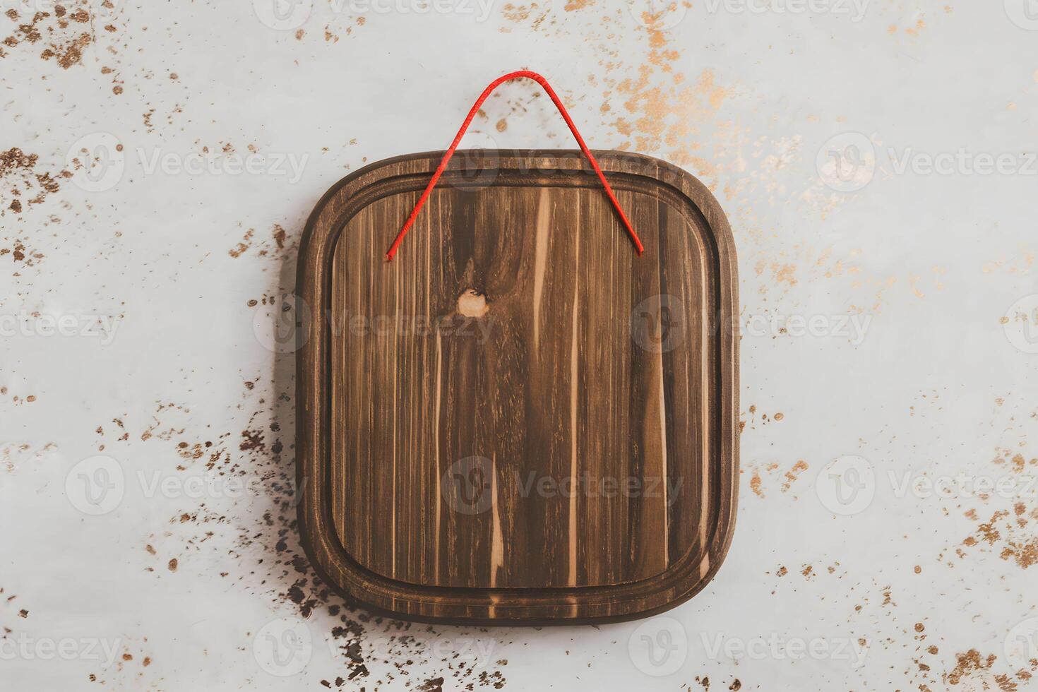 Wooden board with a red string loop adorned with subtle gold specks photo
