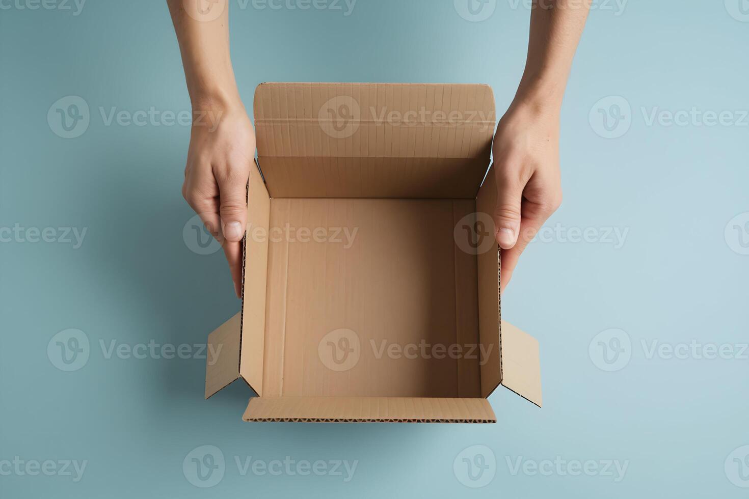 Hands holding an open cardboard box against a blue background photo