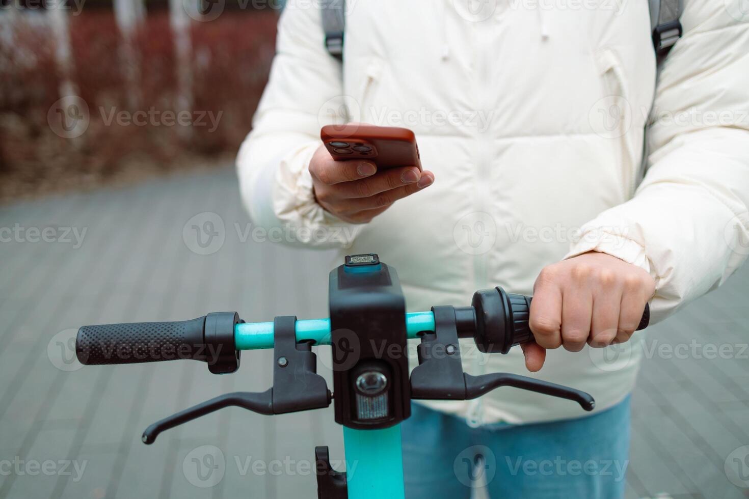 Handsome man using smartphone app. Guy approaches an electric scooter and using mobile phone app NFC contactless locker on bike bicycle in sharing parking lot. photo