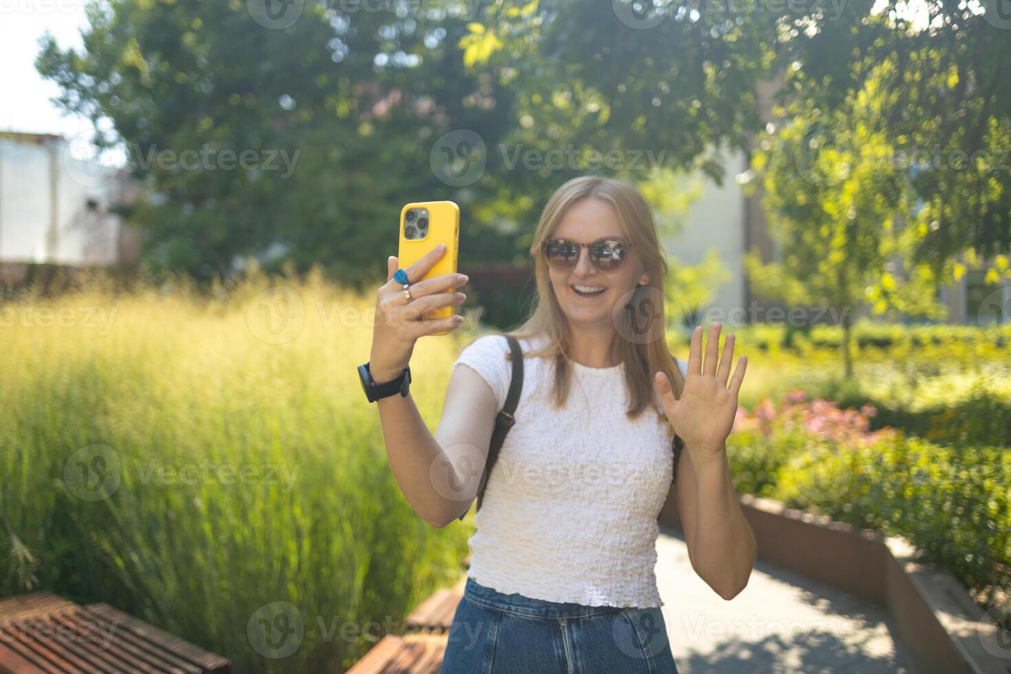 Cheerful smiling 30s lady taking selfie outdoors in city park, happy young female capturing self-portrait while enjoying walk and good day, resting outside photo