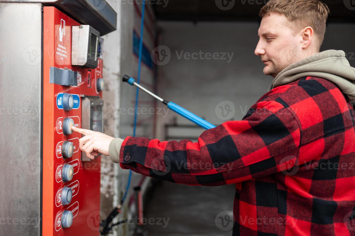 Close up of a hand pressing a button on a self-service coin machine at car wash. photo