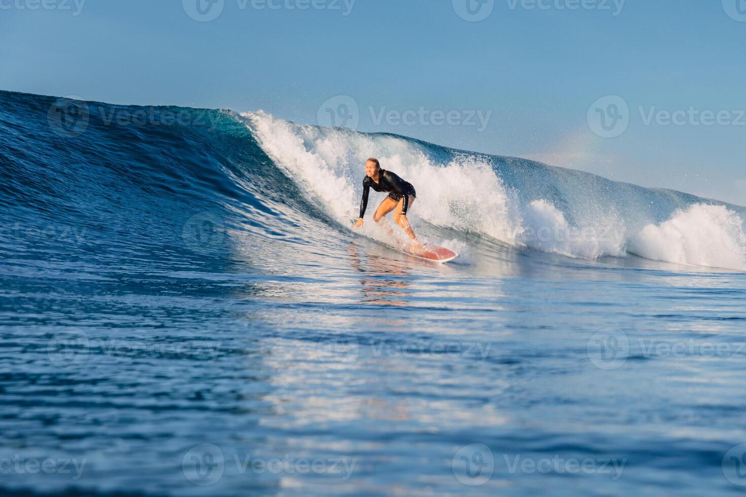 Female surfer on a perfect blue wave in a sunny day and the beauty of surfing in ocean. photo