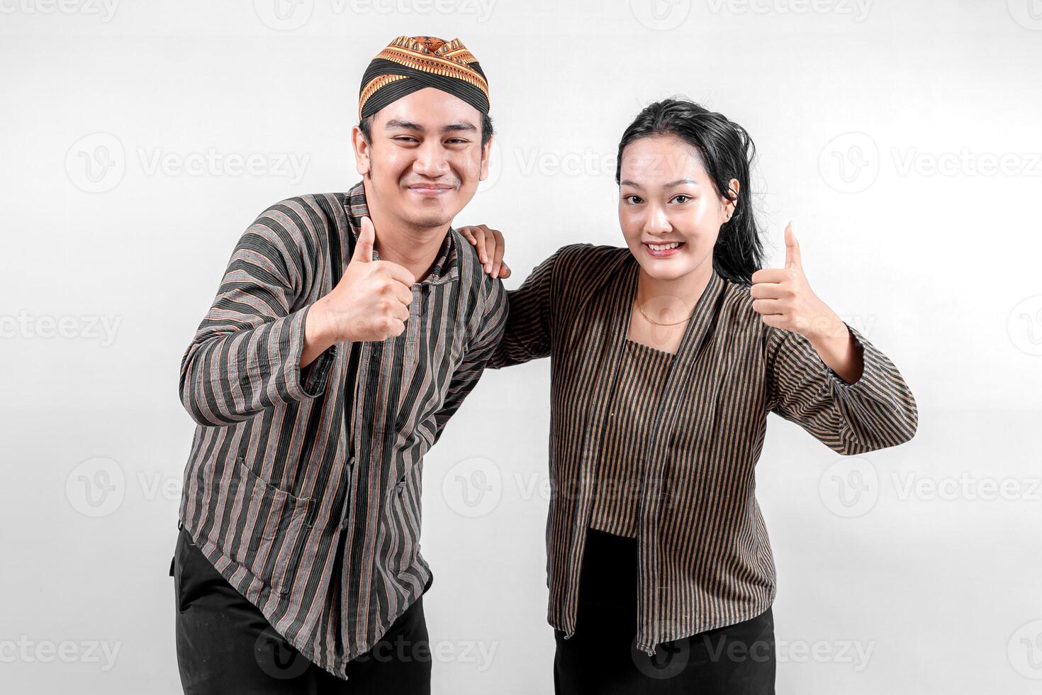 Indonesian couple wearing traditional Javanese Lurik or Sorjan clothing, smiling and showing thumbs up. Ethnic striped outfit symbolizing culture, heritage, and positivity. Isolated on white. photo