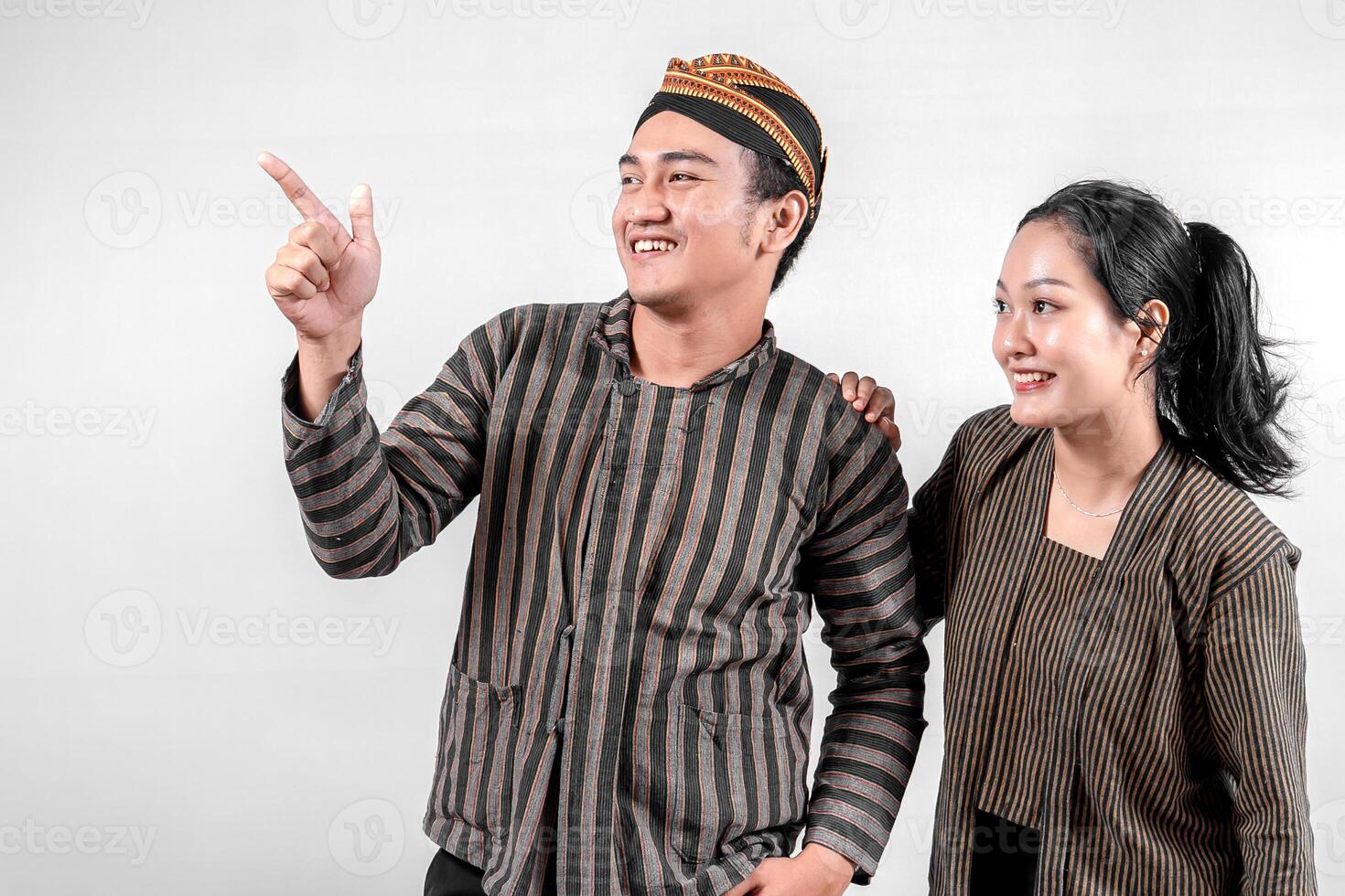 a Indonesian couple wearing traditional Lurik or Sorjan clothing, smiling and pointing. Javanese cultural outfit with striped pattern. Isolated on white background photo