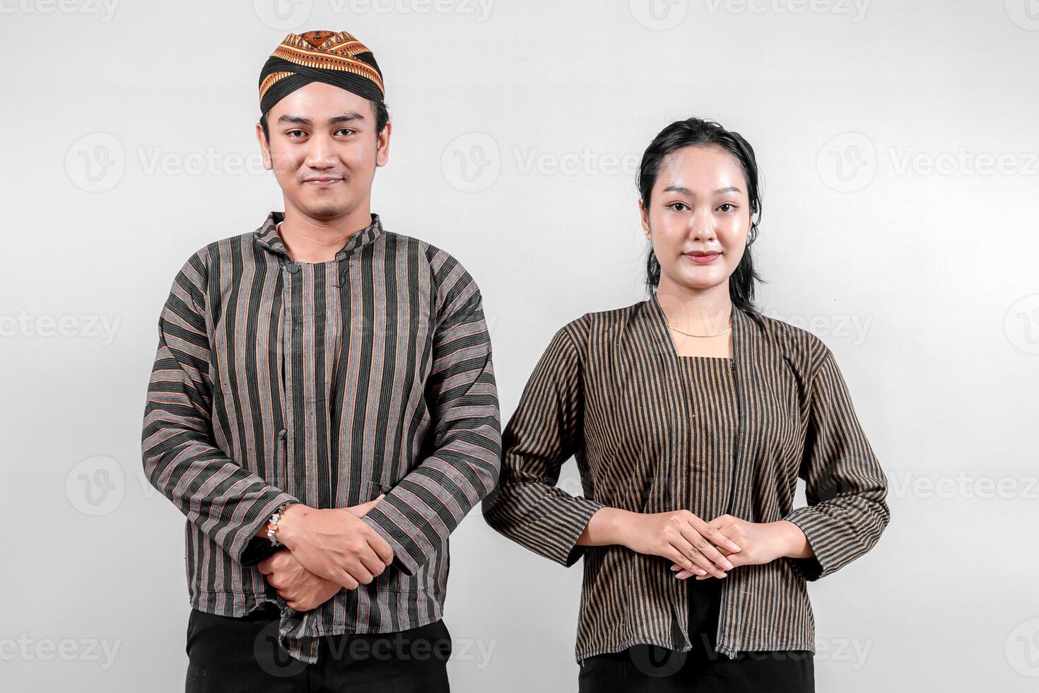 A Indonesian man and a woman, wearing traditional lurik attire expressing a respectful and courteous pose, on a neutral white background. photo