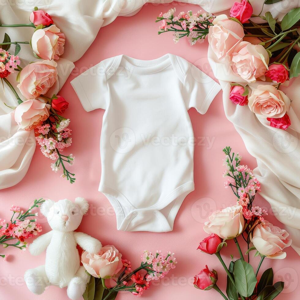 A teddy bear and a baby bodysuit on a pink background photo
