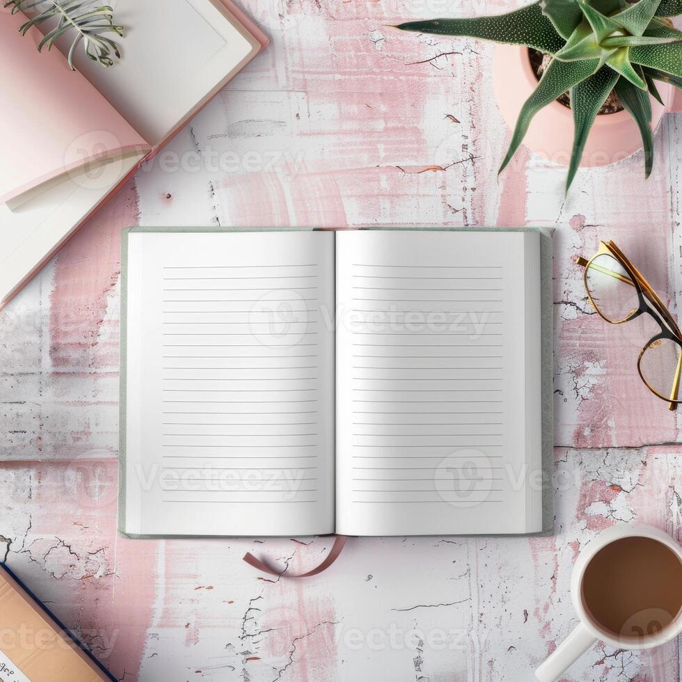 Open notebook, coffee cup, glasses, and book on pink table top view photo