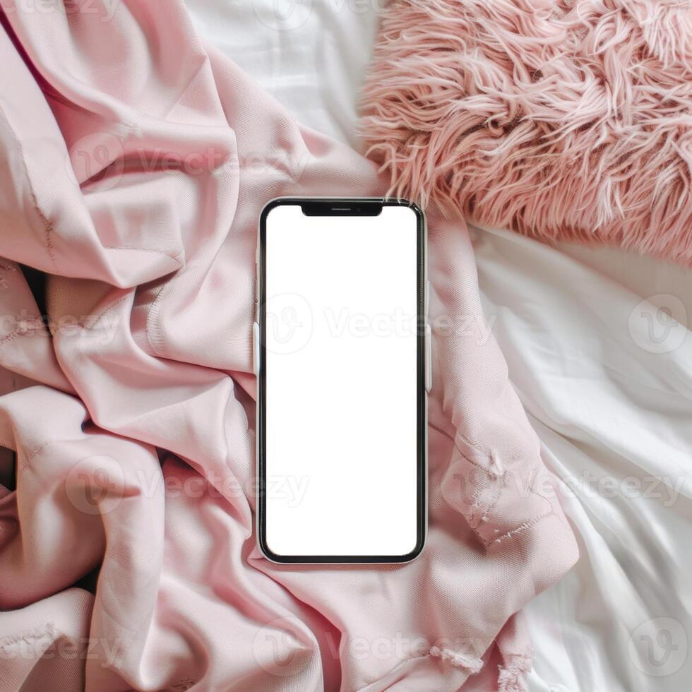 A smartphone is laying on a bed with a pink blanket photo