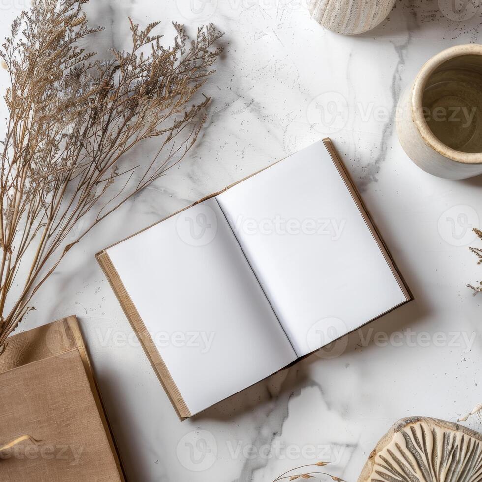 An open book, a cup of coffee and a vase of dried flowers on a marble table photo
