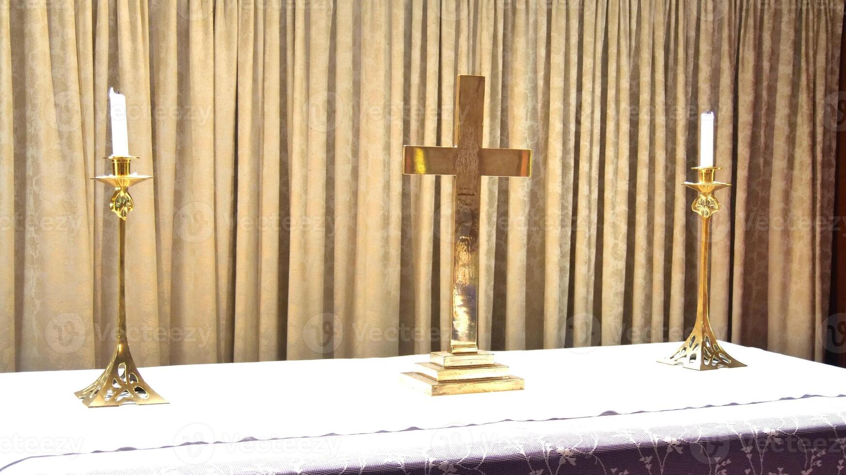 a gold cross and two candles on a table photo