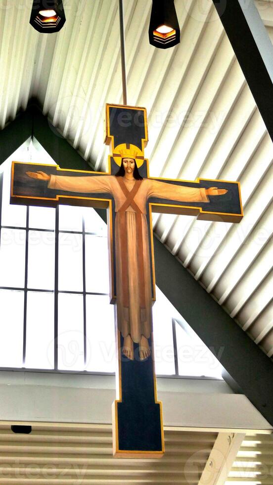 a cross hanging in a church with a window photo