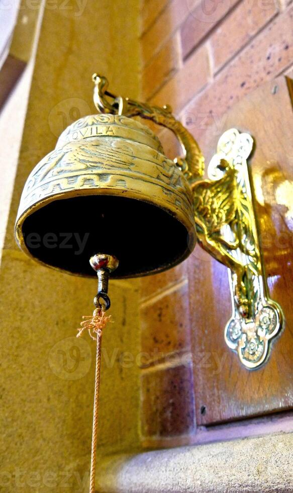 a brass bell hanging from a brick wall photo