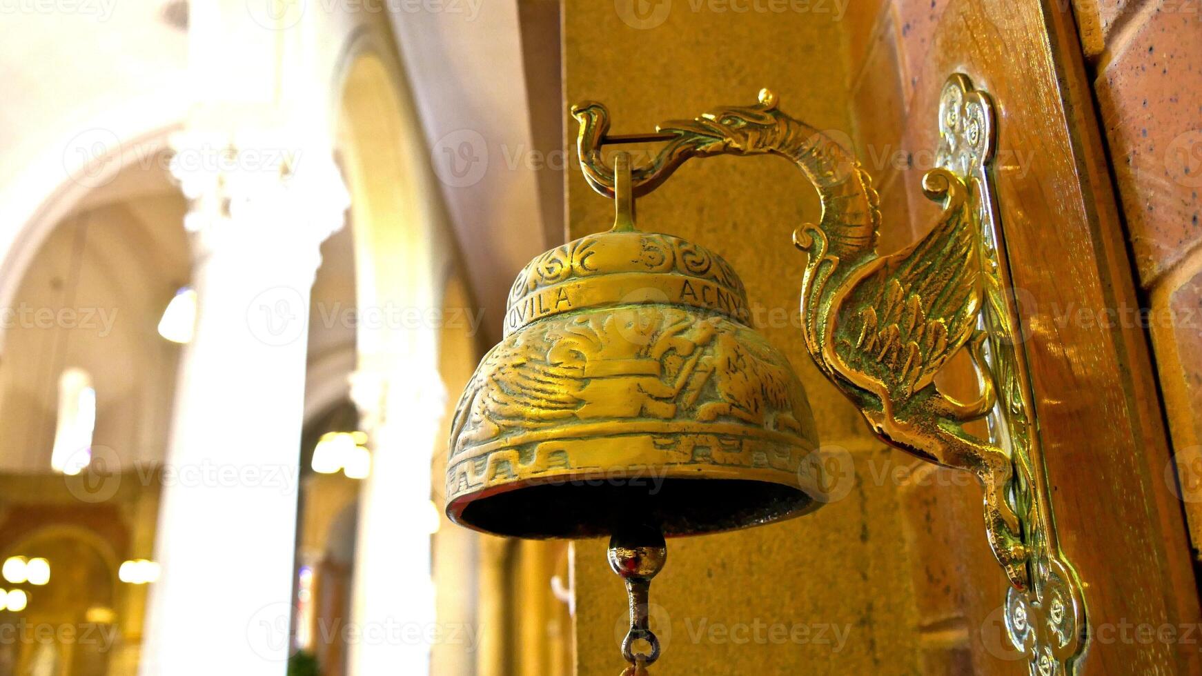 a golden bell hanging on a wall in a church photo