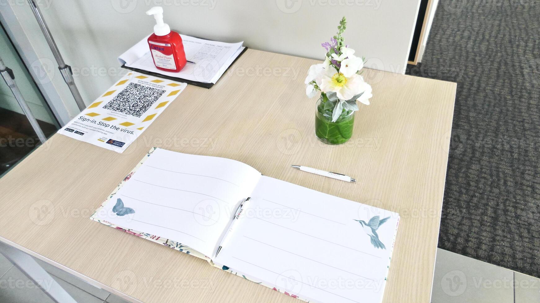 a desk with a notebook, flowers and a vase photo