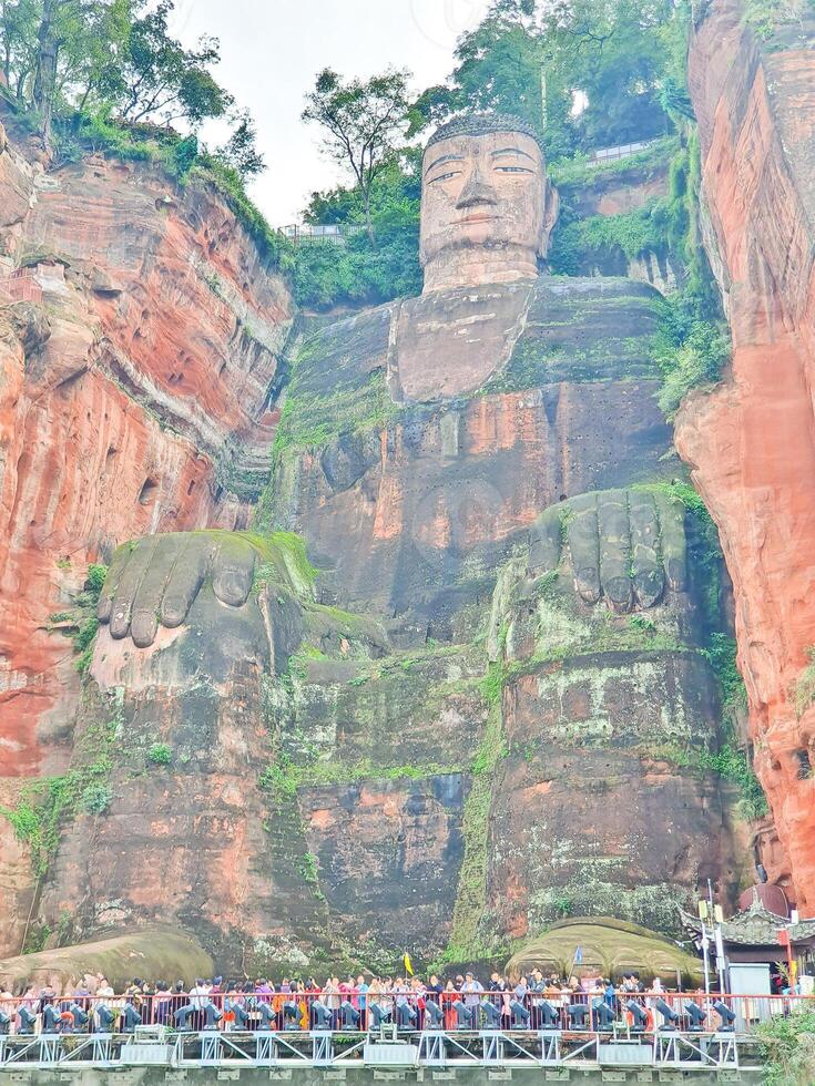 a large statue of a buddha in front of a cliff photo