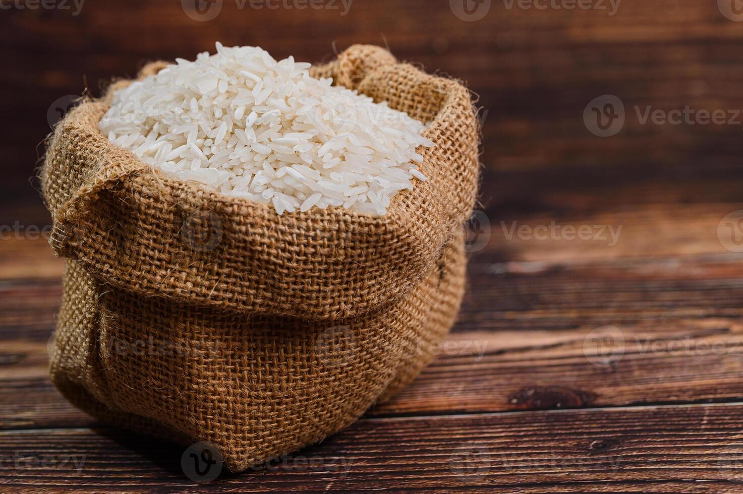 Fresh White Rice in Burlap Sack on Rustic Wooden Background photo