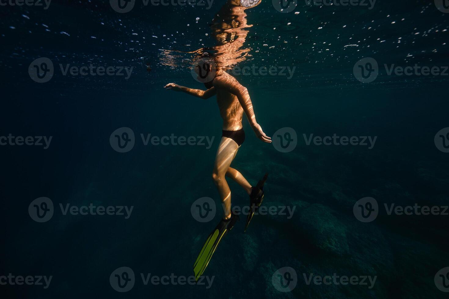 Anonymous male tourist diving undersea in sunlight photo