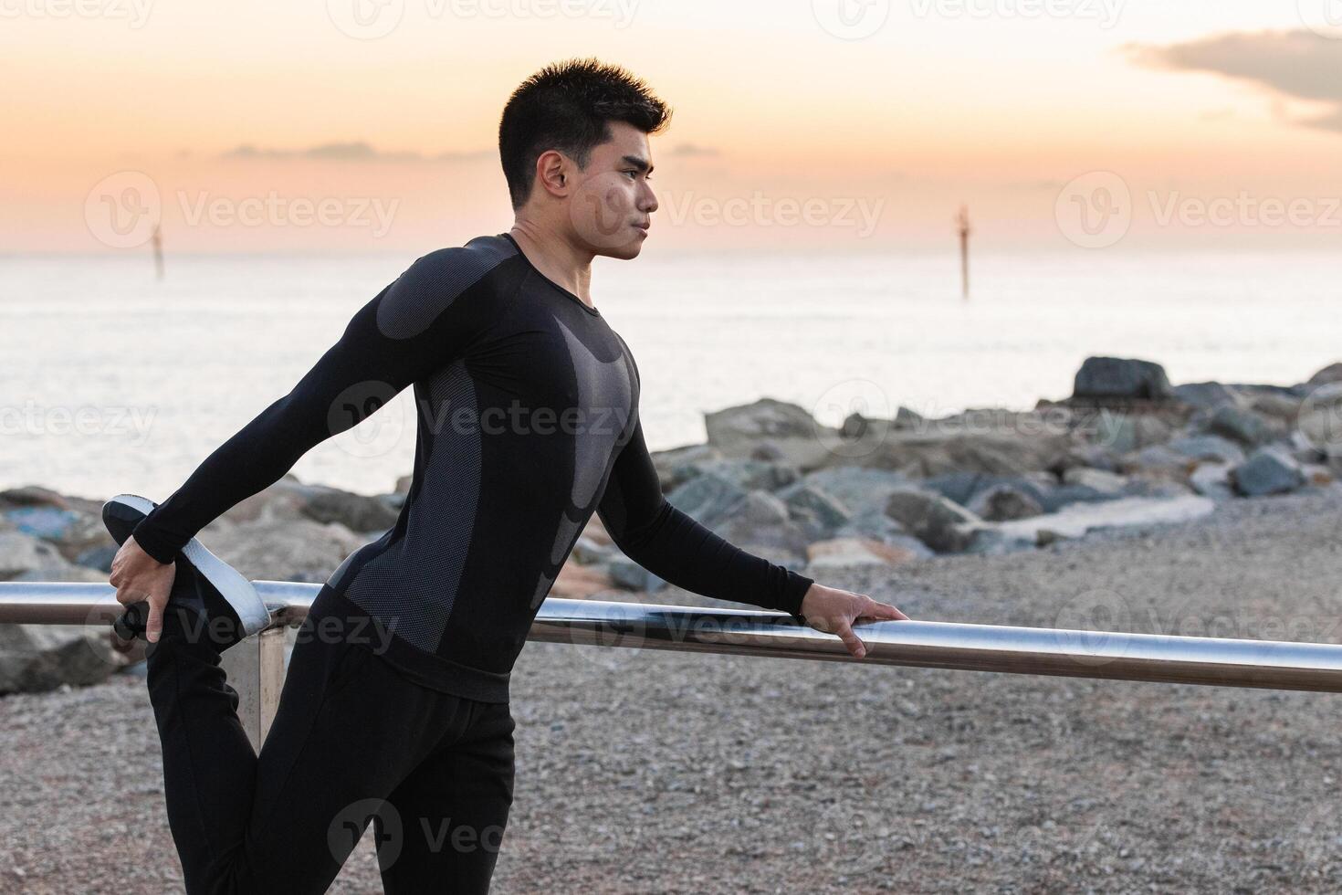Ethnic athlete doing stretching exercise on seashore photo