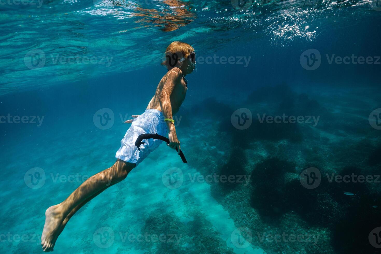 Boy in diving mask swimming underwater photo
