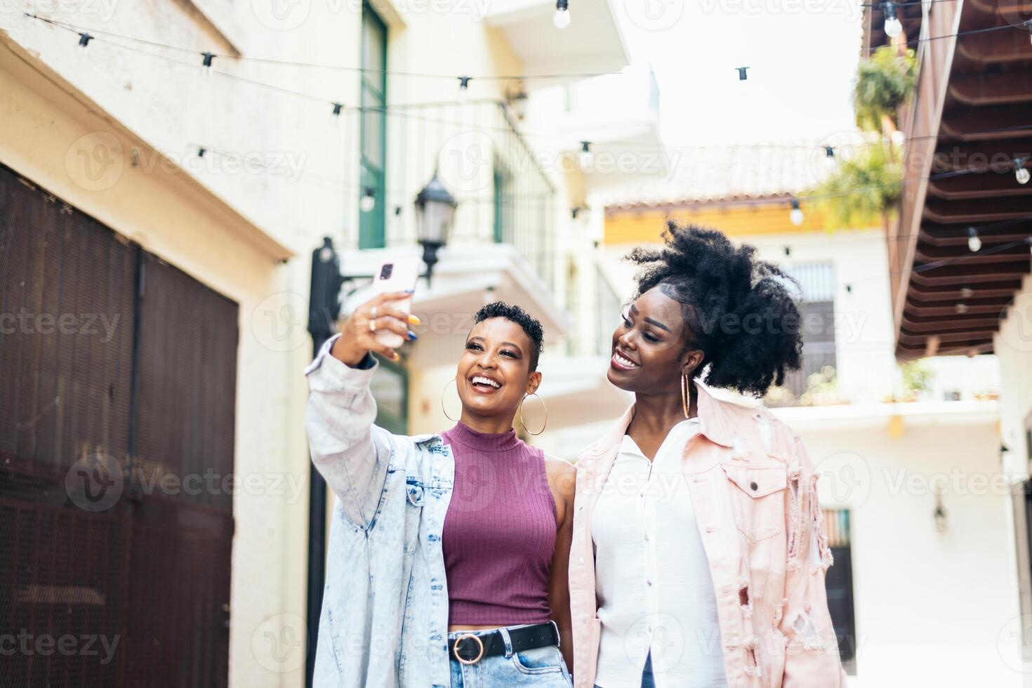 Happy women taking selfies with smartphone walking in the city photo
