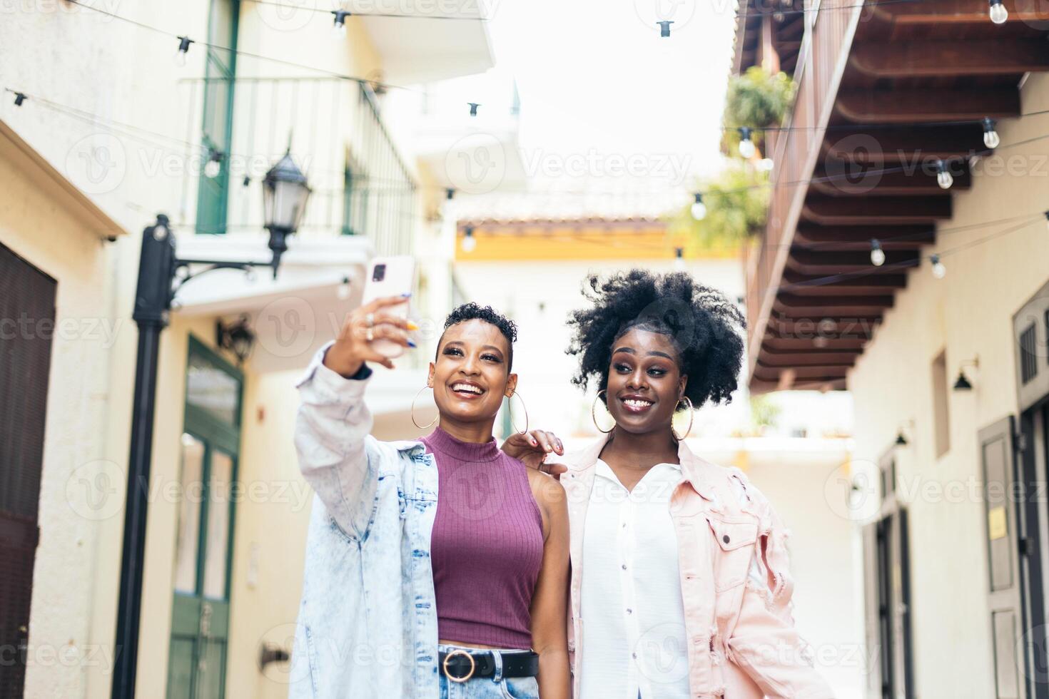 Happy adult women taking selfies with smartphone walking in the city photo
