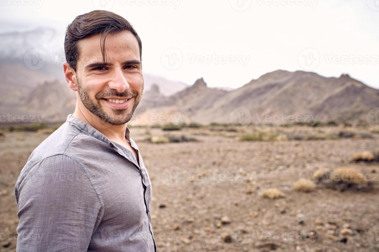 Positive man standing in mountainous area in cloudy day photo