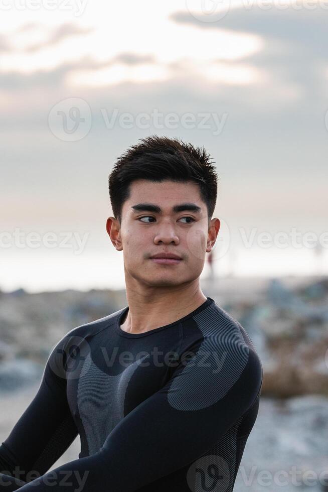 Ethnic sportsman stretching near sea photo
