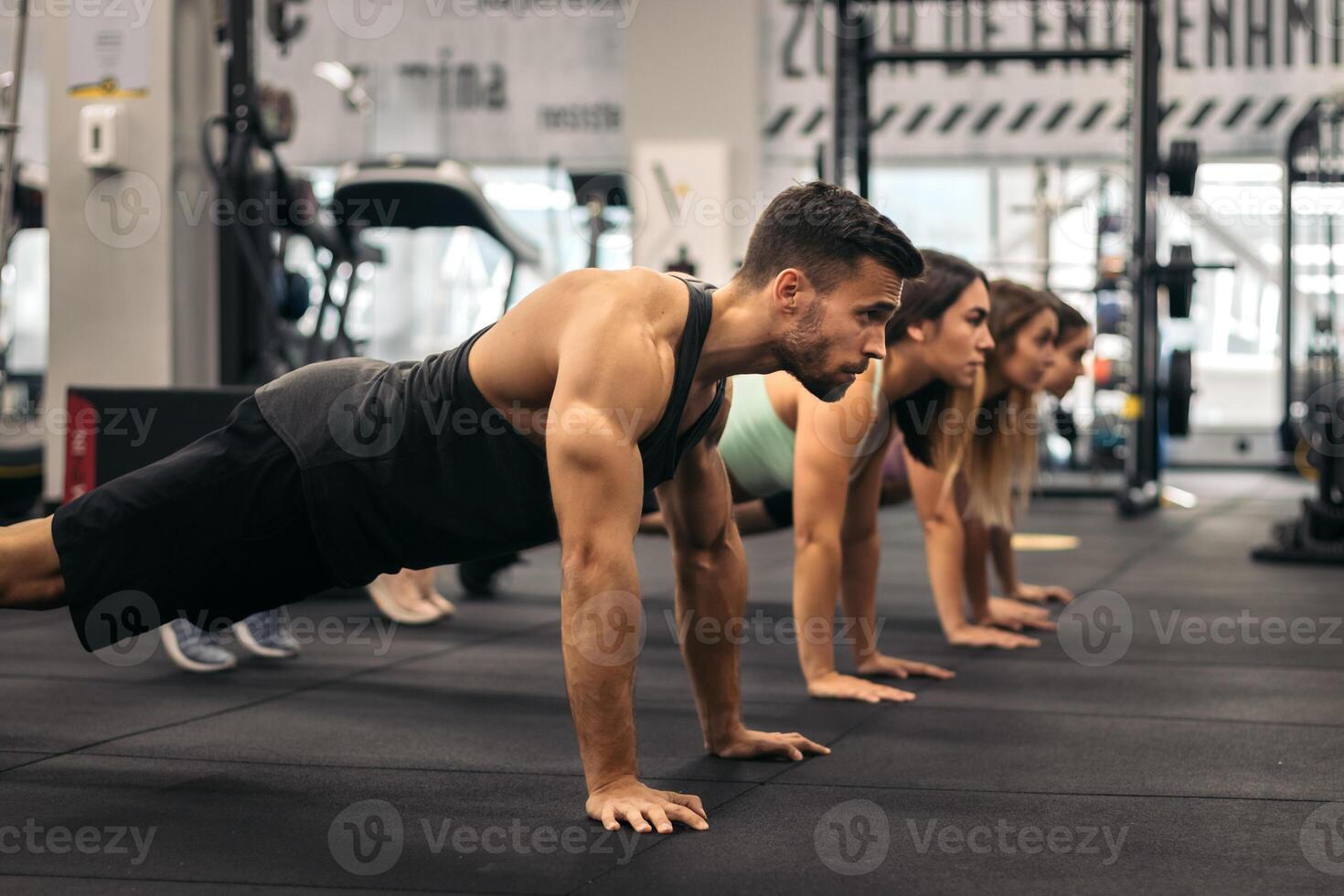 group of young people doing push ups in a gym. Training in progress photo