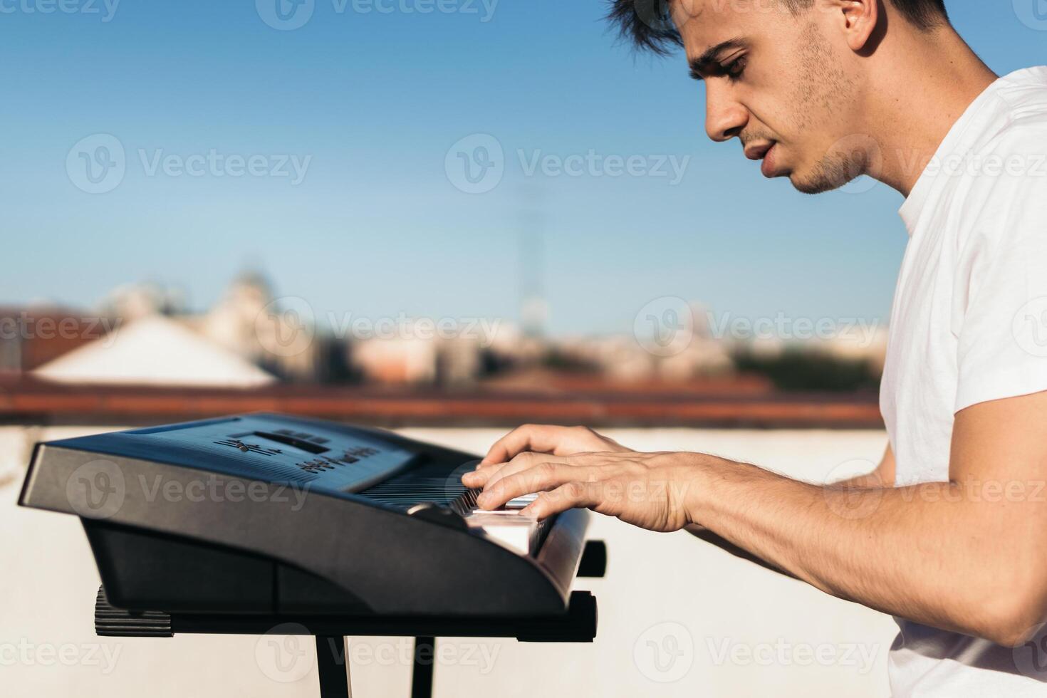 man playing piano on an urban rooftop alone photo