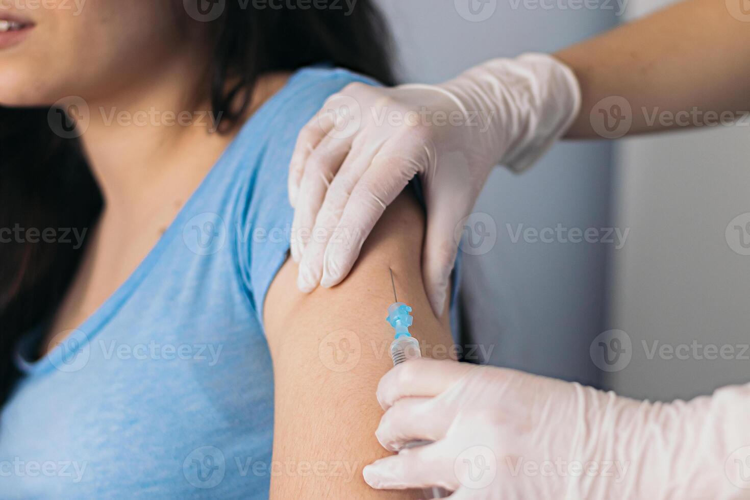 Doctor working with patient's arm. Physician or nurse giving vaccination and immunity to virus, influenza or HPV with syringe. Appointment with medical expert photo