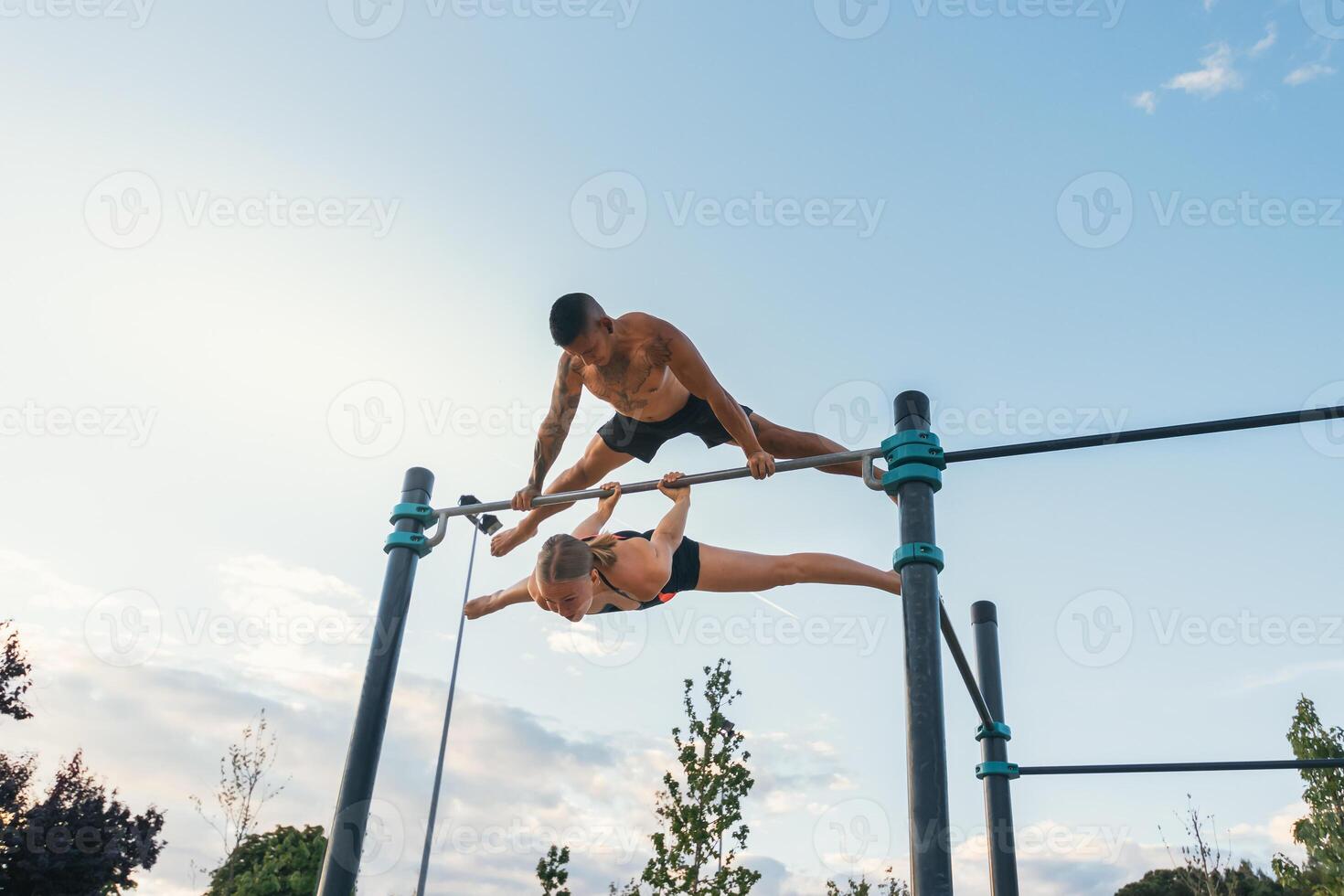 couple training together in a calisthenics park. doing back lever and straddle planche. photo