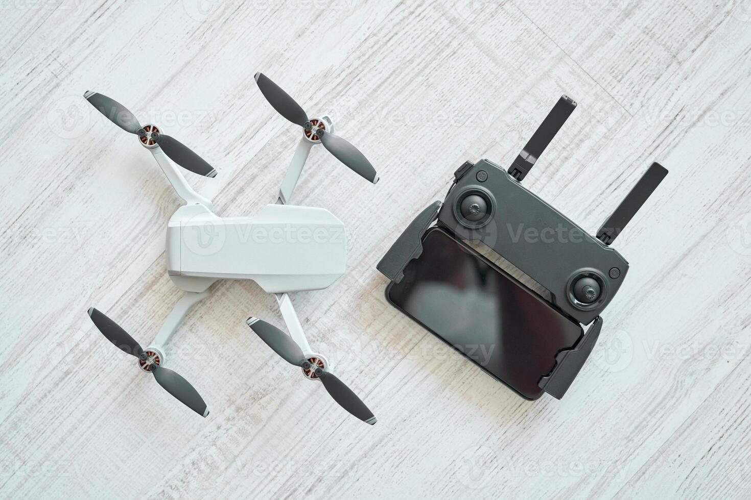 New modern drone with remote control panel placed on floor photo
