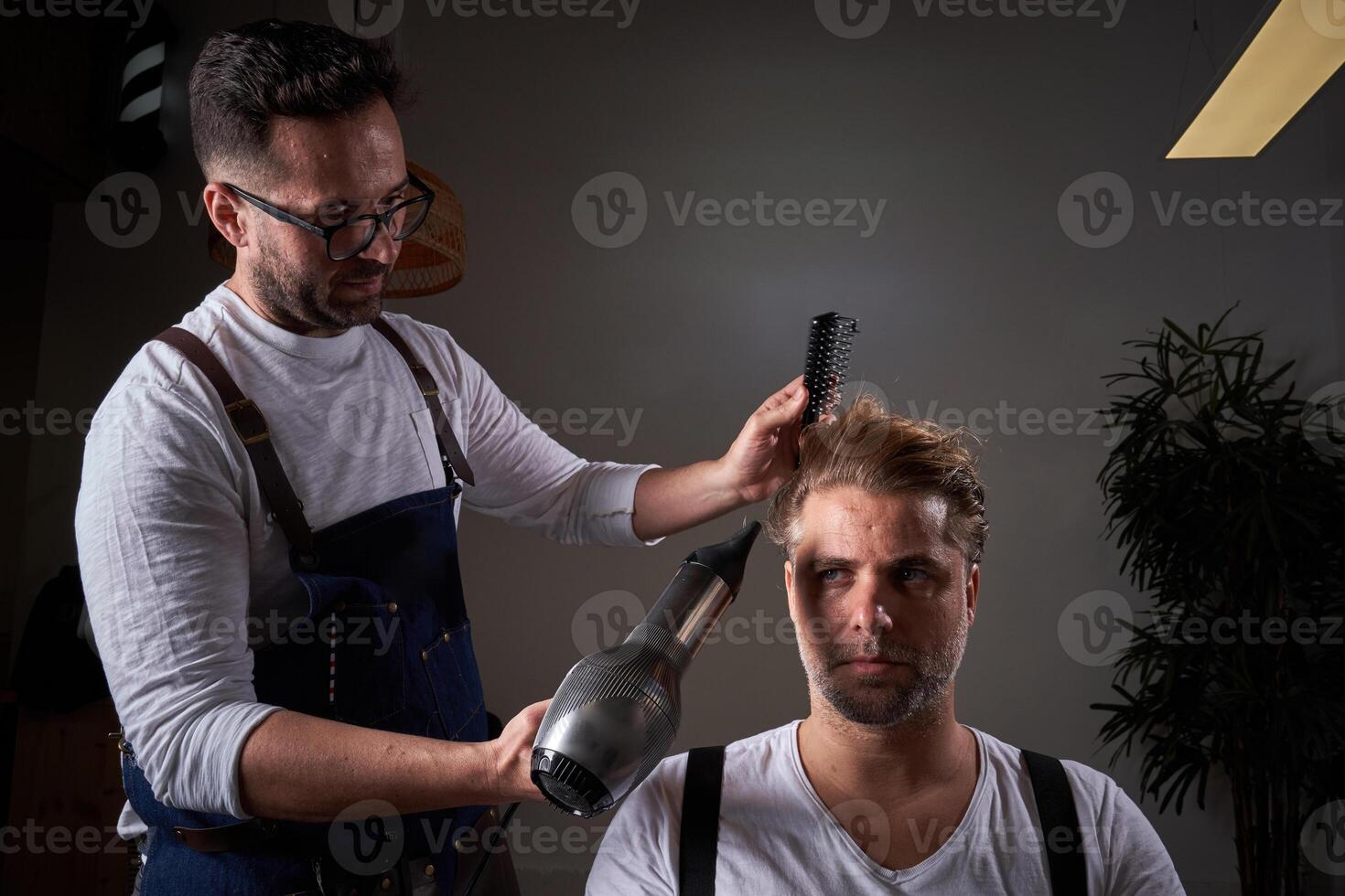 Concentrated barber drying hair of client photo