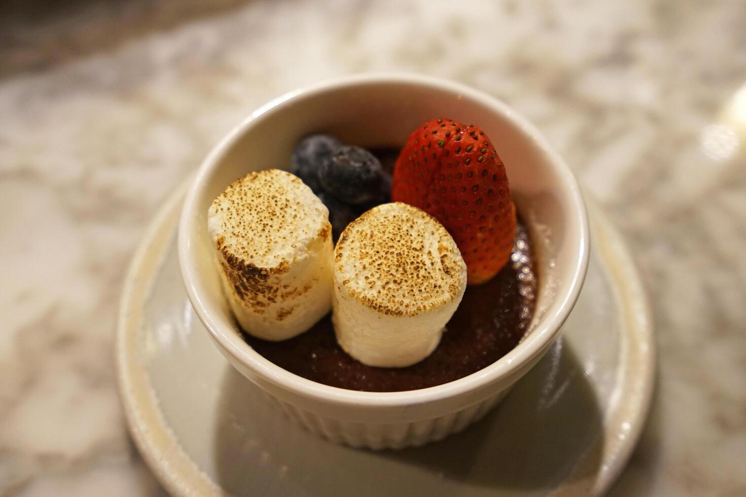 Close up bowl of grilled marshmallows and mixed berries topped on chocolate mousse photo