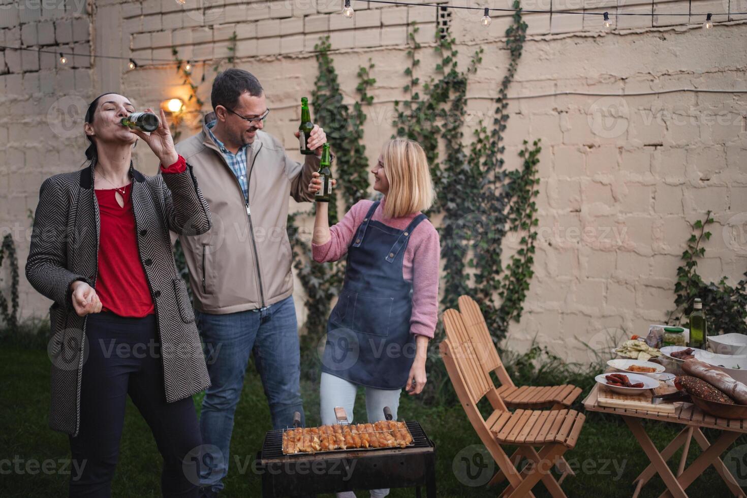 Friends celebrate outdoors with a barbecue and laughter in the evening glow photo